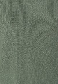 Groene gebreide stof met een fijne ribbeltextuur, die een effen kleur laat zien zonder patronen of accenten.