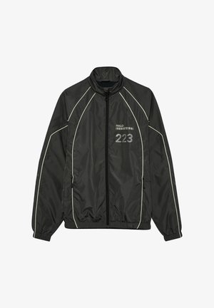 Czarna sportowa kurtka na zamek z białym wykończeniem, elastycznymi mankietami i dołem, z napisem "HALO 196819721981 223" po prawej stronie przodu.