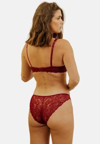 Ensemble de lingerie en dentelle bourgogne comprenant un soutien-gorge et une culotte, ornés de motifs floraux, avec des bretelles réglables et des bords festonnés, dévoilant un design délicat et féminin.