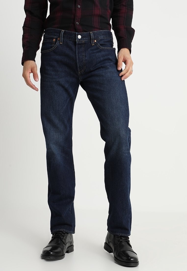 Jeans de mezclilla azul oscuro con un diseño de pierna recta, que cuentan con cinco bolsillos y costuras en contraste. Llevados con botas negras hasta el tobillo.