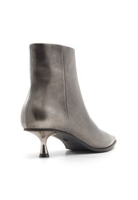 Botín de tobillo de cuero gris con una punta redondeada y elegante, textura suave y un tacón en forma de cono metálico. Un brillo sutil acentúa el diseño.