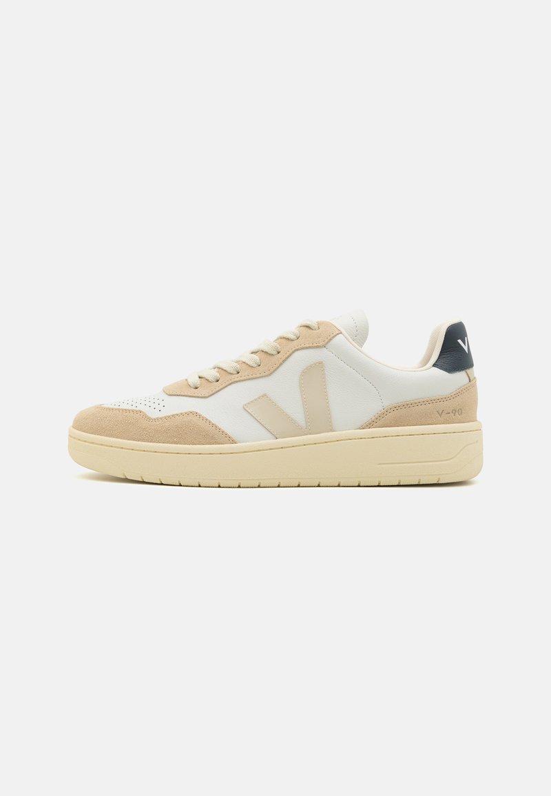 Weiße und beige Leder-Sneaker mit Wildlederdetails, die ein Schnürdesign, eine perforierte Zehenbox und eine kontrastierende marineblaue Fersenschlaufe aufweisen.