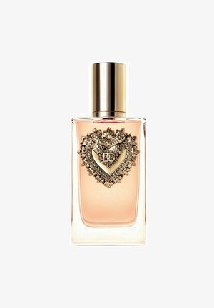 Flacon de parfum en verre parfumé avec un liquide rose, accent en forme de cœur doré avec un détail complexe et un bouchon doré.