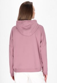 Hoodie van zacht roze stof met een losse pasvorm, drop schouders en geribbelde manchetten. Eenvoudig ontwerp, minimale naden en geen zichtbare graphics.