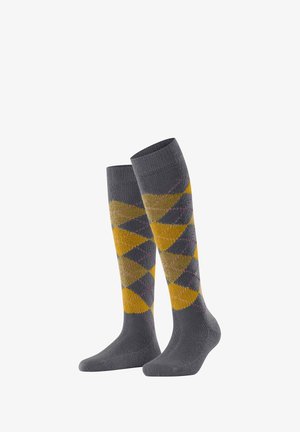 Les chaussettes montantes présentent un fond gris avec un motif argyle jaune et gris, rehaussé de lignes roses.