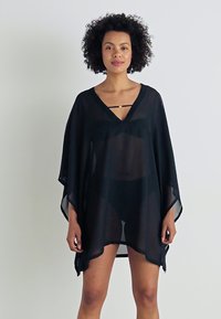 Čierny priehľadný kaftan s výstrihom do V, voľnými rukávmi a dekoračným zlatým akcentom okolo výstrihu. Ľahký, prúdny materiál.