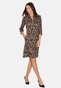 Schwarz-beige gestreiftes Zebra-Print-Kleid mit Kragen, Dreiviertelärmeln und Seitentaschen, aus leichtem Stoff gefertigt.