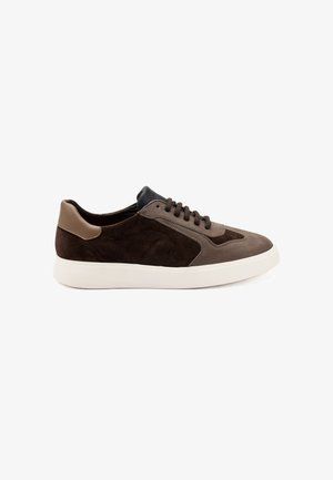 Zapatillas de ante marrón con acentos de cuero marrón claro, suela de goma blanca y lengüeta negra en contraste. Cuenta con cierre de cordones y punta redondeada.