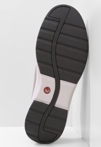 Semelle de chaussure avec un dessous en caoutchouc noir texturé, une midsole blanche et un logo rouge circulaire. Elle présente des motifs rainurés pour l'adhérence.