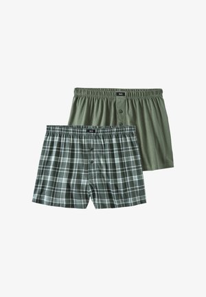 Two pairs of boxers: one solid olive green, one dark green plaid with white lines. Both feature elastic waistbands and front button closures.