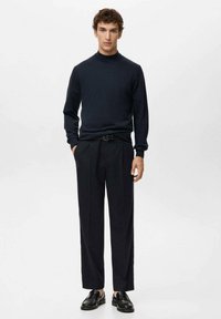 Granatowy golf w połączeniu z czarnymi spodniami z wysokim stanem. Czarna elegancka para butów dopełnia stylizację. Gładka tekstura, casualowy design, dopasowany krój.