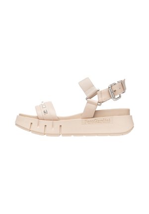 Sandalias de plataforma beige con parte superior de cuero suave, correa ajustable en el tobillo y tachuelas decorativas plateadas. Suela texturizada con patrón acanalado.