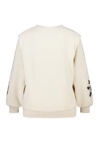 Roomkleurige sweatshirt met een ronde hals, doorlopende schoudernaad en geribbelde manchetten. Heeft een zwarte bloemrijke borduring op de linkermouw.