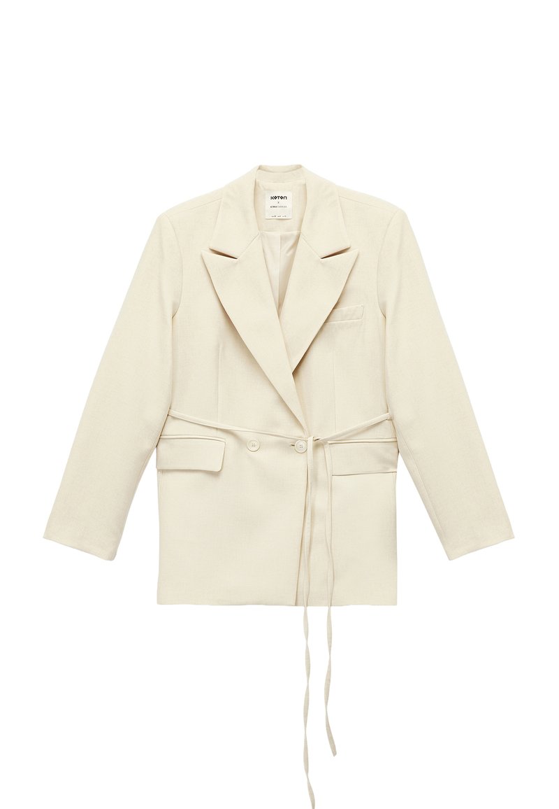 Jasnobeżowa dopasowana marynarka z podwójnym zapięciem na guziki, dużymi klapami, bocznymi kieszeniami i paskiem do wiązania. Wykonana z materiału o fakturze.