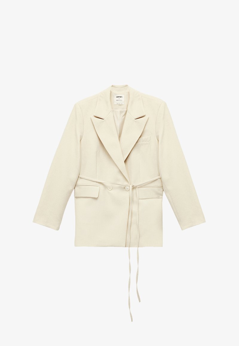 Jasnobeżowa dopasowana marynarka z podwójnym zapięciem na guziki, dużymi klapami, bocznymi kieszeniami i paskiem do wiązania. Wykonana z materiału o fakturze.