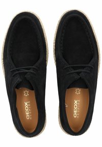 Zapatos de ante negros con punta redonda, plantilla en contraste color tostado y suela con borde de yute. Cuentan con cordones y detalles de costura.