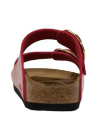 Sandaletta rossa con due cinturini regolabili, hardware dorato, plantare in sughero e suola in gomma nera. Design piatto adatto per l'uso quotidiano.