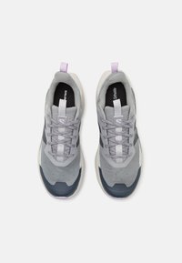 Une paire de baskets de sport grises et noires avec des languettes lavande, des lacets à motifs et des semelles rembourrées, montrées en vue de dessus.