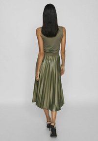 Vestido verde oliva con un top sin mangas y una falda de satén con pliegues. Cintura ajustada con una textura suave y diseño hasta los tobillos.