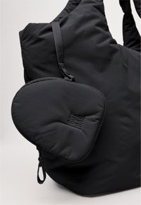 Svart vadderad toteväska med en liten avtagbar ficka. Har texturerad tyg och präglad "GOT BAG"-logga på fickan.