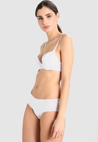 Set di reggiseno e slip bianco, tessuto liscio, forma sagomata, bretelle regolabili, design minimalista, dettaglio con chiusura davanti, bordi senza cuciture.