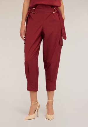 Pantalones cargo burdeos de longitud hasta el tobillo con cintura ajustable, que presentan detalles en dorado, bolsillos laterales y una textura de tela suave.