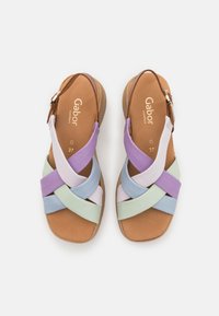 Sandal multicolore con fasce viola, azzurro chiaro e verde menta, caratterizzata da un design a fascia incrociata e una suola imbottita color sabbia.