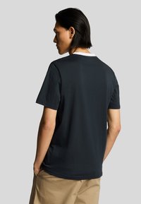 Maglietta blu scuro con colletto rotondo e maniche corte. Realizzata in cotone, presenta un design semplice e un accento di colletto bianco.