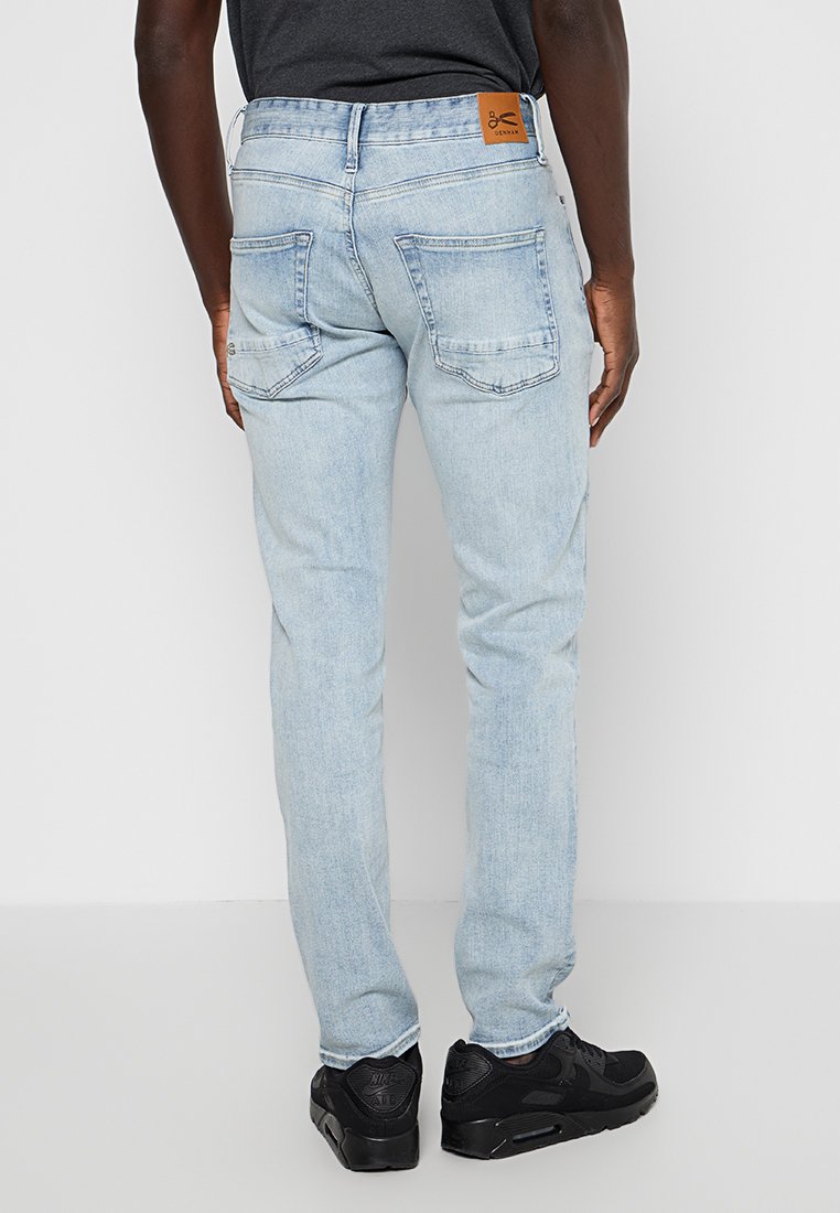 Lichtblauwe denim jeans met een rechte pasvorm, voorzien van twee achterzakken en een tan leren merkpatch op de tailleband.