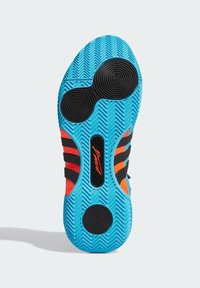 Semelle de chaussure avec un fond en caoutchouc bleu présentant un motif en chevron, des accents noirs et des rayures oranges. Éléments de bande de roulement circulaires inclus.