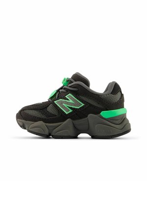 Baskets New Balance noires et grises avec des touches de vert, dessus en mesh et suède, semelle épaisse texturée et fermetures sécurisées.