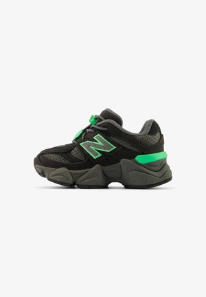 Baskets New Balance noires et grises avec des touches de vert, dessus en mesh et suède, semelle épaisse texturée et fermetures sécurisées.