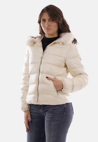 Giacca a piumino color avorio con cerniera frontale, cappuccio foderato in pelliccia e polsini elastici. Presenta una texture trapuntata e tasche laterali.