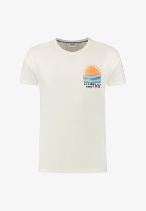 Kermanvärinen puuvillapaita, jossa on graafi auringosta sinisten raitojen yllä ja teksti "CHASING SUN SINCE 1960" rinnassa.