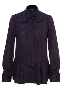 Marinblå blus med röda prickar, lättviktstyg, hög krage med rosett, långa ärmar med samlade manschetter och en utsvängd peplumkant.