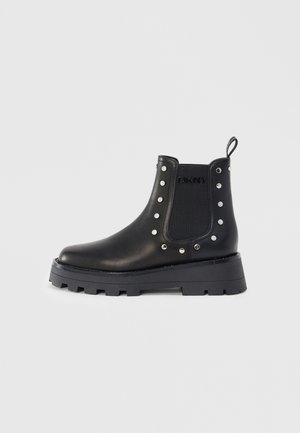 Svarta läder Chelsea-boots med kraftig sula, silver nitar som omger det elastiska sidopanelen, dragflik och diskret DKNY-logotyp.