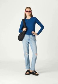 Μπλε μπλούζα με μακριά μανίκια σε συνδυασμό με ανοιχτό μπλε σκισμένα τζιν. Η μαύρη τσάντα με επένδυση και οι μαύρες πλατφόρμες ολοκληρώνουν το σύνολο.