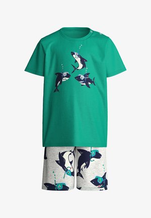 Chemise verte et short gris avec des requins dessinés portant des masques de plongée et des bulles qui montent au-dessus d'eux.