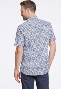 Camicia a maniche corte in tessuto leggero, caratterizzata da un motivo floreale con tonalità di blu, verde e viola, orlo dritto e colletto.