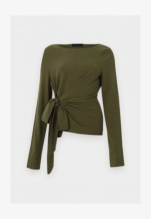 Olivgrüne Langarmbluse mit Bootsausschnitt und seitlichem Knotendetail, das drapierte Falten erzeugt.
