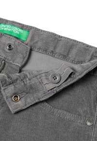 Šedé kordové kalhoty s zelenou etiketou, kovovým knoflíkem a zipem. Obsahují kapsu a detaily v šití. Měkká textura a žebrovaný design.