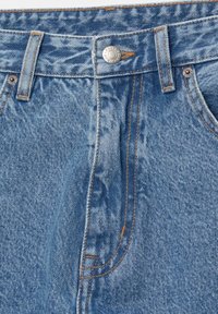 Světle modré džíny z denimu s klasickým pětipocket designem, vyznačující se kontrastním oranžovým prošíváním a stříbrným zapínáním na knoflík.