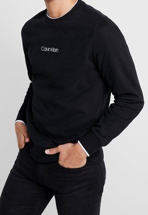 Sudadera negra de algodón con el logotipo blanco de Calvin Klein. Presenta cuello redondo, mangas largas y acentos blancos en los puños.