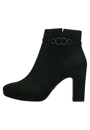Stivaletto in velluto nero con tacco alto a blocco, punta affusolata e una fascia decorativa con cerchi intrecciati attorno alla caviglia.
