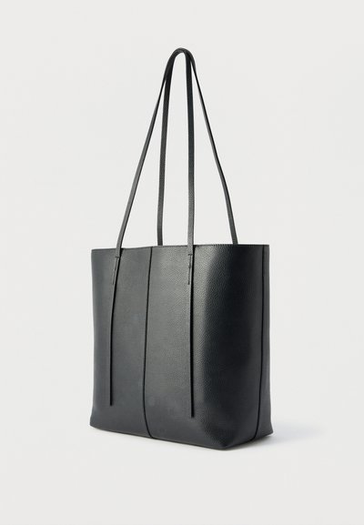 Μαύρη τοσέτ τσάντα από υφή δέρματος με δύο μακριές λουριά ώμου και μια κάθετη ραφή στη μέση, φωτογραφημένη σε ουδέτερο φόντο.