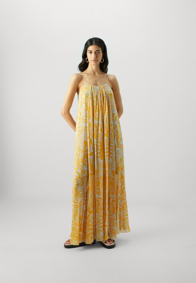 Vestido maxi amarillo con patrones abstractos en blanco, que presenta un corte holgado y tirantes finos. Hecho de una tela ligera y fluida.