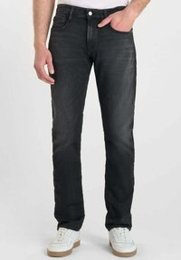 Jean en denim noir avec une coupe droite, design à cinq poches et fermeture à boutons. Le tissu a un léger éclat et une texture lisse.