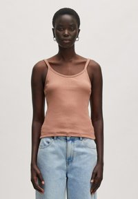 Brauner gerippter Tanktop mit dünnen Trägern, ausgestattet mit einem runden Ausschnitt und einer enganliegenden Silhouette. Kombiniert mit hellblauen, hoch taillierten Jeans.