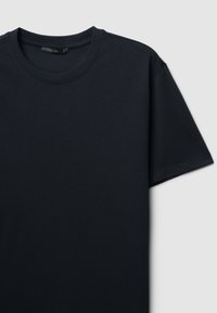 T-shirt in cotone nero con colletto rotondo, maniche corte e una finitura ribattuta con texture. Design semplice, cuciture piatte e nessun logo o dettaglio visibile.