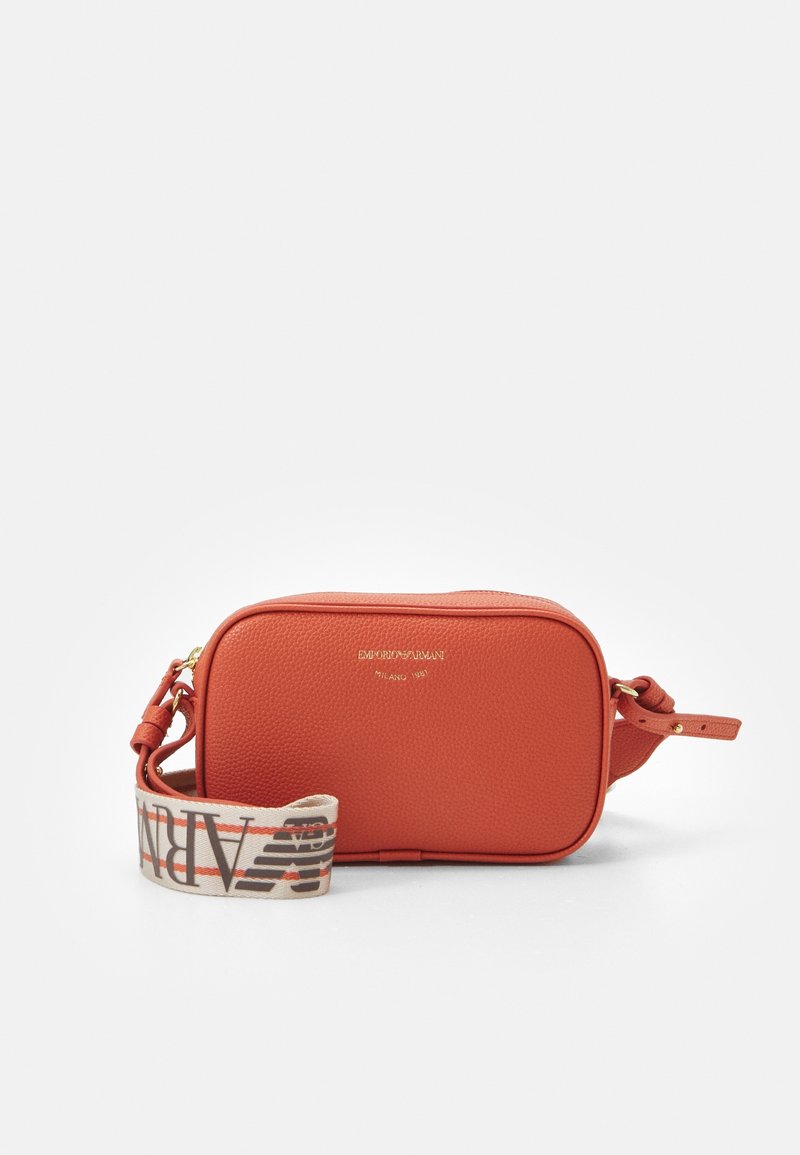 Red pebbled leather crossbody bag with gold hardware and a patterned canvas strap featuring text. Rectangular shape with zip closure.
